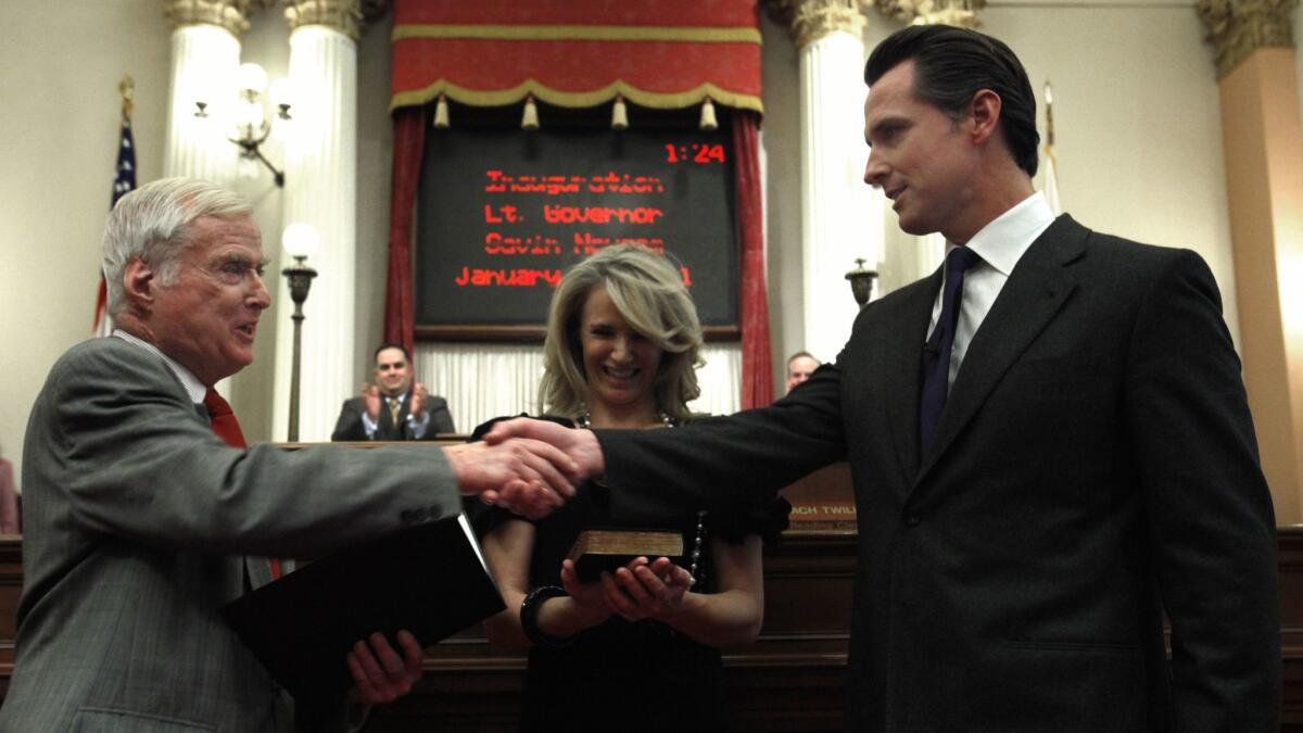 Gavin Newsom, right, shakes hands with his father, William Newsom, a former justice of the state Court of Appeal, who swore his son into office as lieutenant governor in 2011. Gavin Newsom's wife, Jennifer Siebel Newsom is shown in the middle.