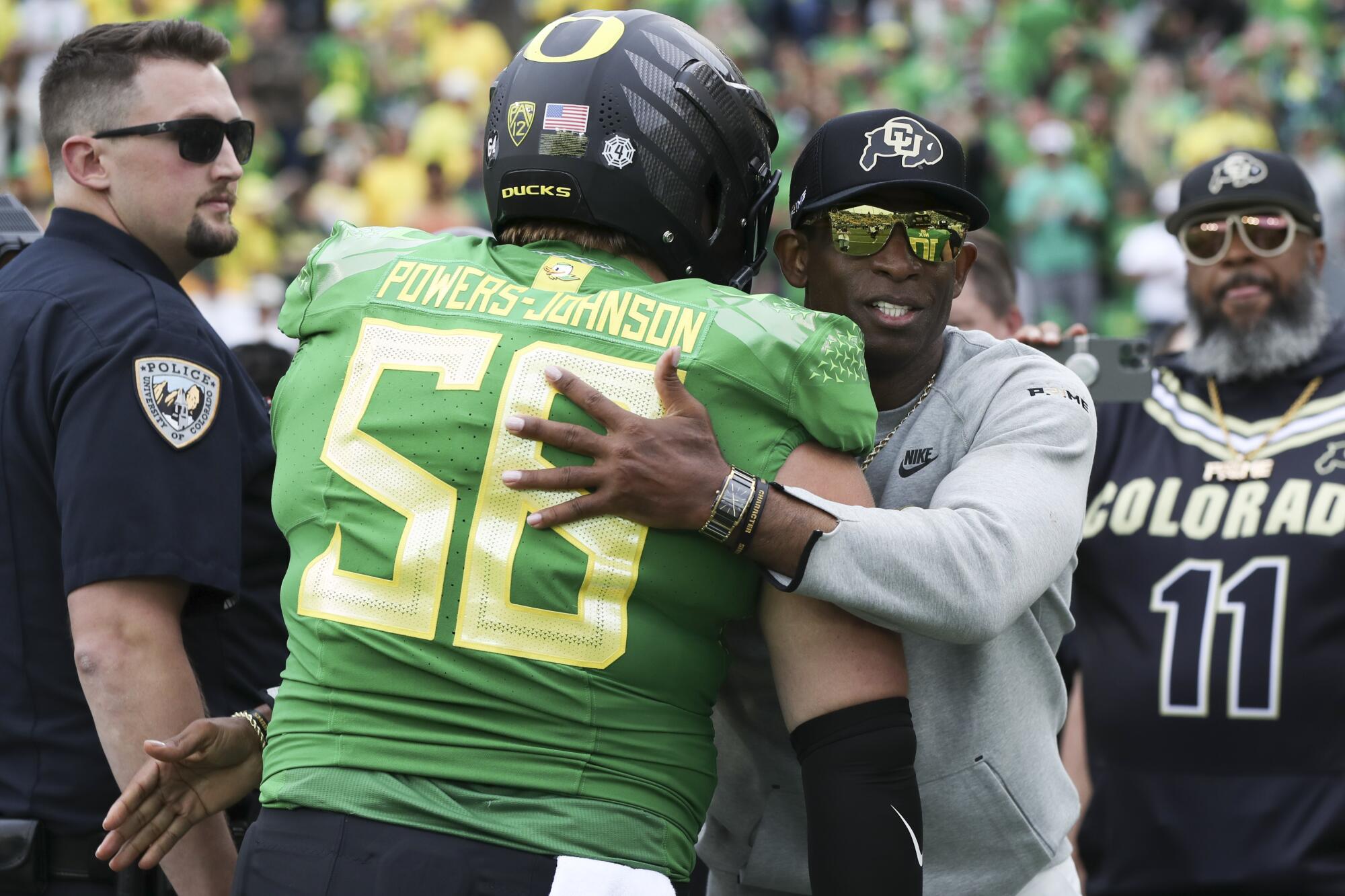 Colorado coach Deion Sanders hugs Oregon offensive lineman Jackson Powers-Johnson on the sideline