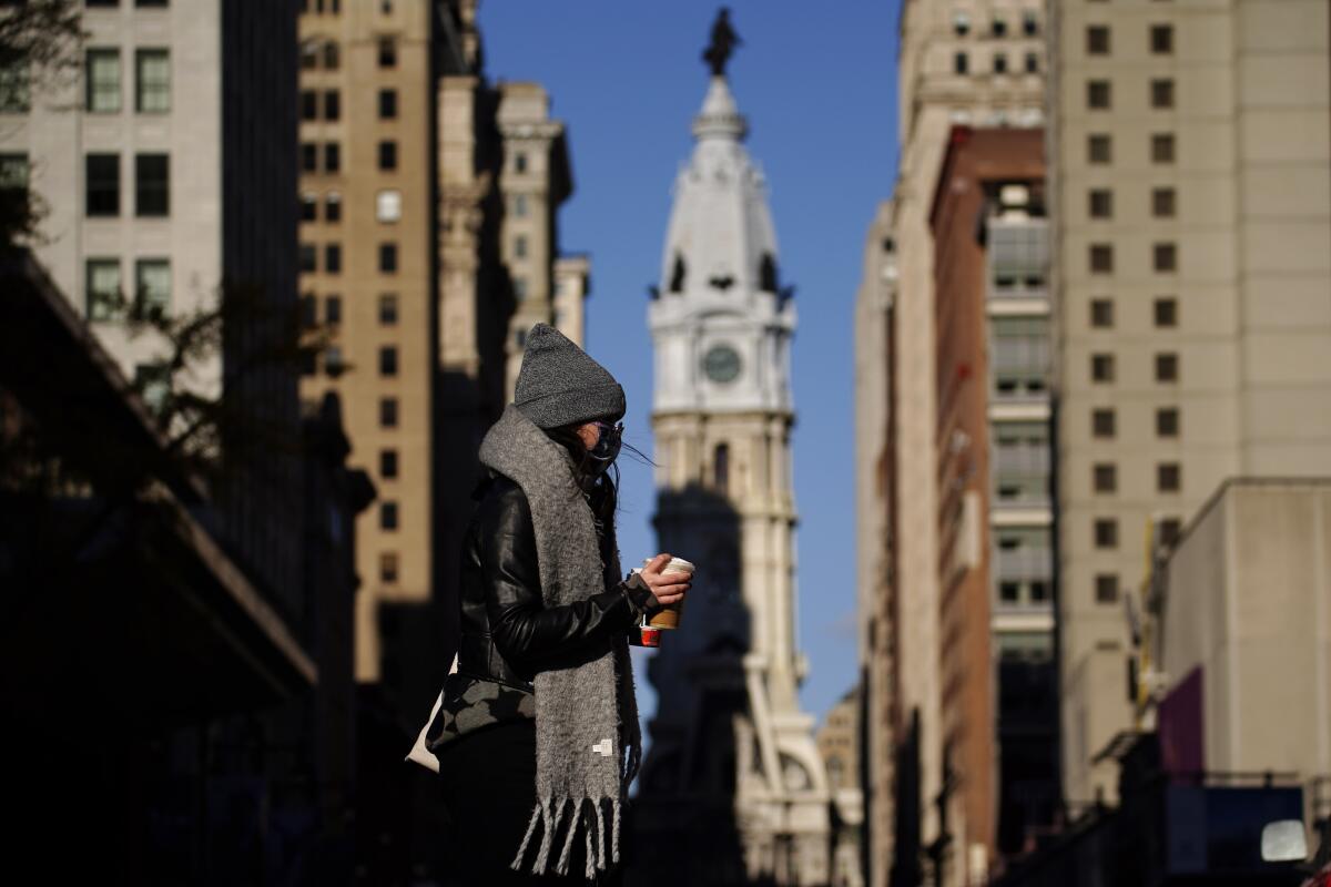 Una persona con mascarilla cruzando la calle Broad en Filadelfia. 