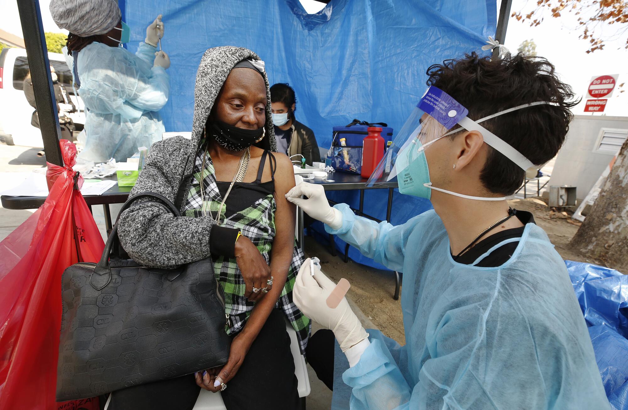 Registered nurse Kevin Hernandez vaccinates Bernadette Klines at Leimert Plaza Park.