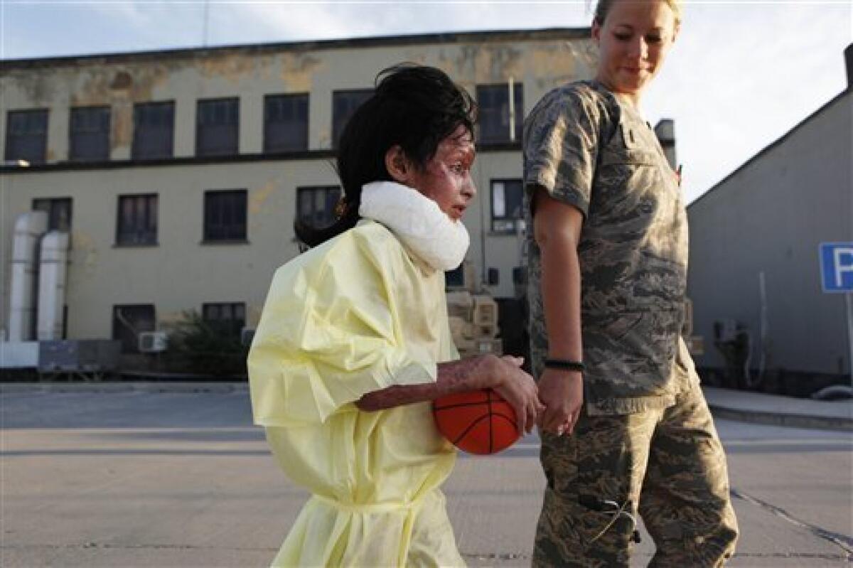 In this photo taken Thursday, June 11, 2009, Lt. Michelle Smith, of Boise, Idaho, holds hands with 8-year-old Razia at Bagram Air Base, north of Kabul, Afghanistan. Razia was evacuated to the hospital in May after she was severely burned when a white phosphorus round hit her home in the Tagab Valley, killing two of her sisters during fighting between French troops and Taliban militants. (AP Photo/Rafiq Maqbool)