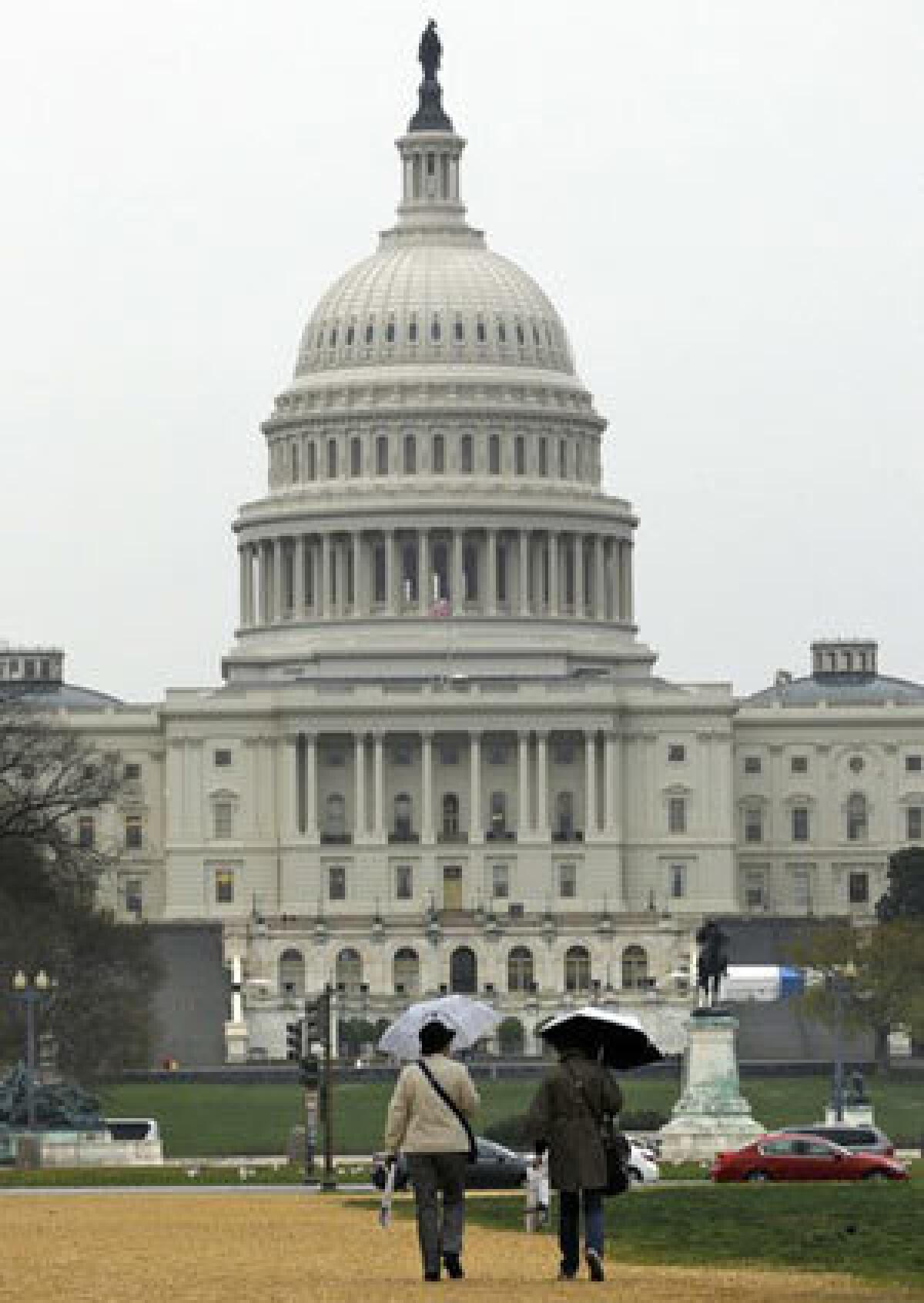 People walk in the rain on the National Mall in Washington, toward the Capitol as Congress continues to debate in hopes of avoiding a government shutdown.