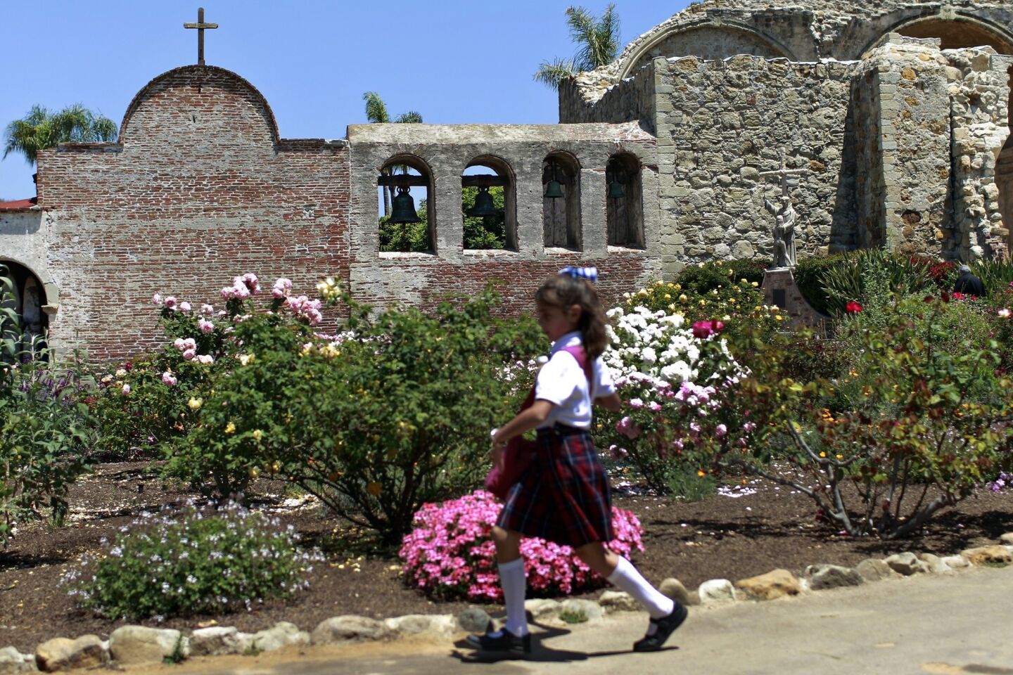 A young girl runs past the blooming gardens inside Mission San Juan Capistrano. The gardens have helped make this mission among the state's most popular.