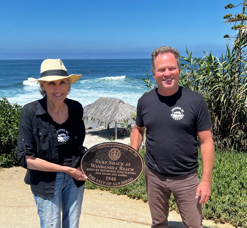 Melinda Merryweather and Jim Neri stand with the new historical plaque for the Windansea surf shack.