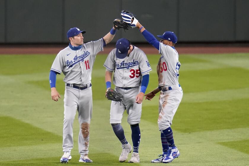 Dodgers outfielders, from left, A.J. Pollock, Cody Bellinger and Mookie Betts celebrate a win over the Mariners.