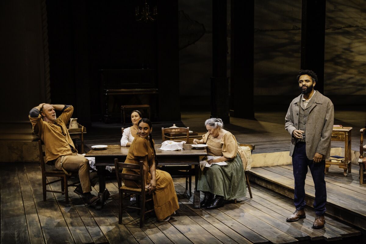 Costumed "Uncle Vanya" cast members are gathered around a table onstage at Pasadena Playhouse.