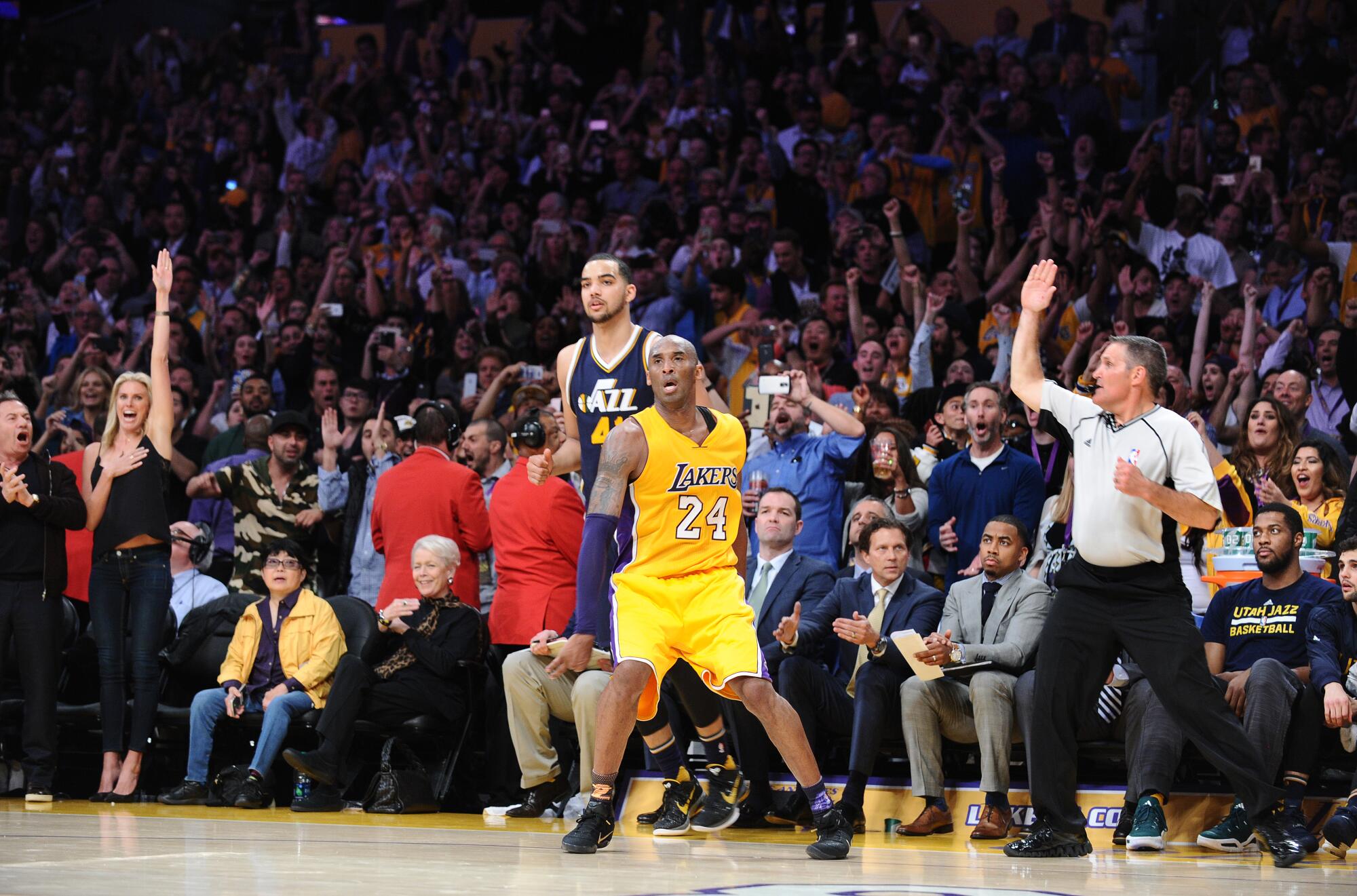 Referee Monty McCutchen signals for three points after Kobe Bryant sank a long-range shot in his farewell game.