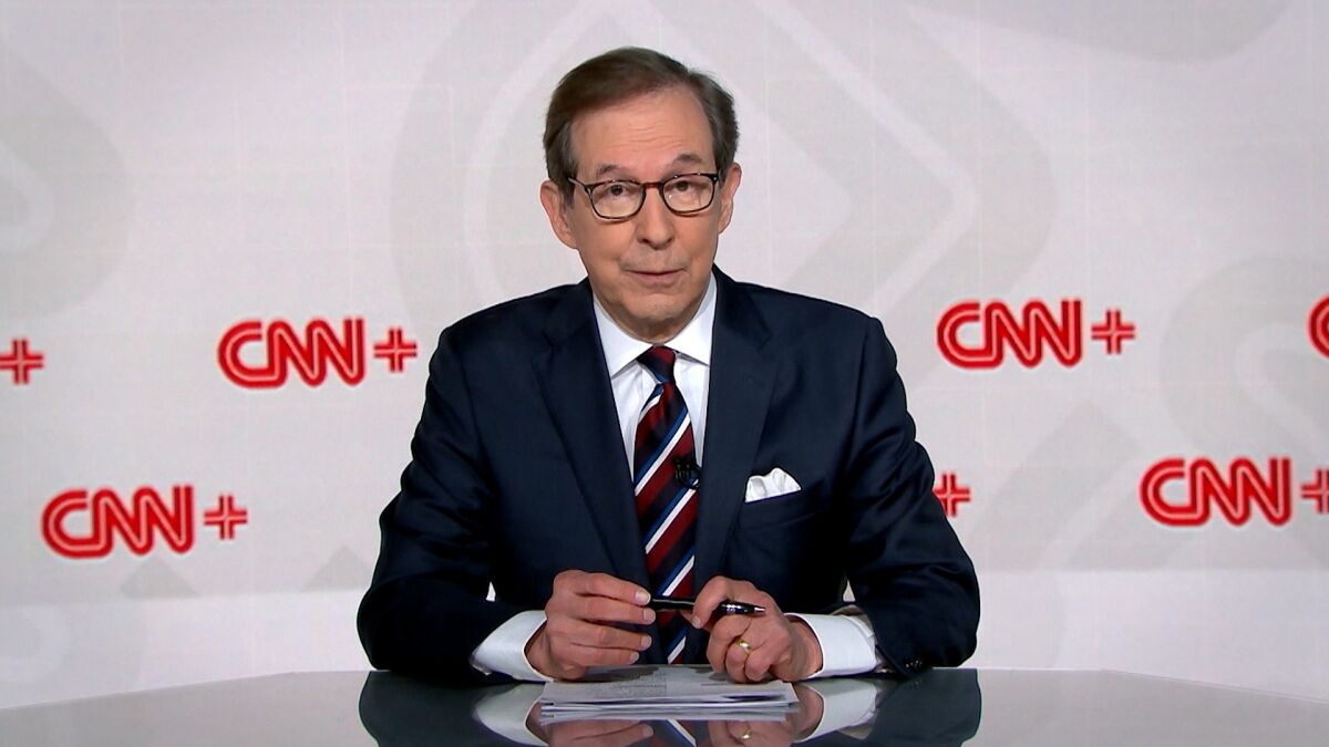 Chris Wallace sits in front of a CNN+ logo