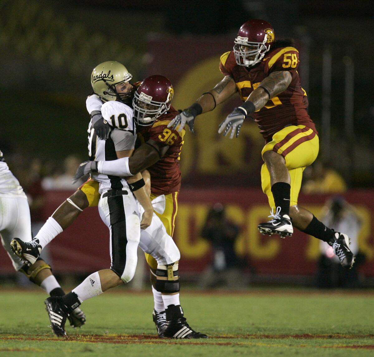 After throwing a pass, Idaho quarterback Nathan Enderle is hit by USC defensive lineman Lawrence Jackson as linebacker Rey Maualuga helps defend during the first half Sept. 1, 2007. USC won 38–10.