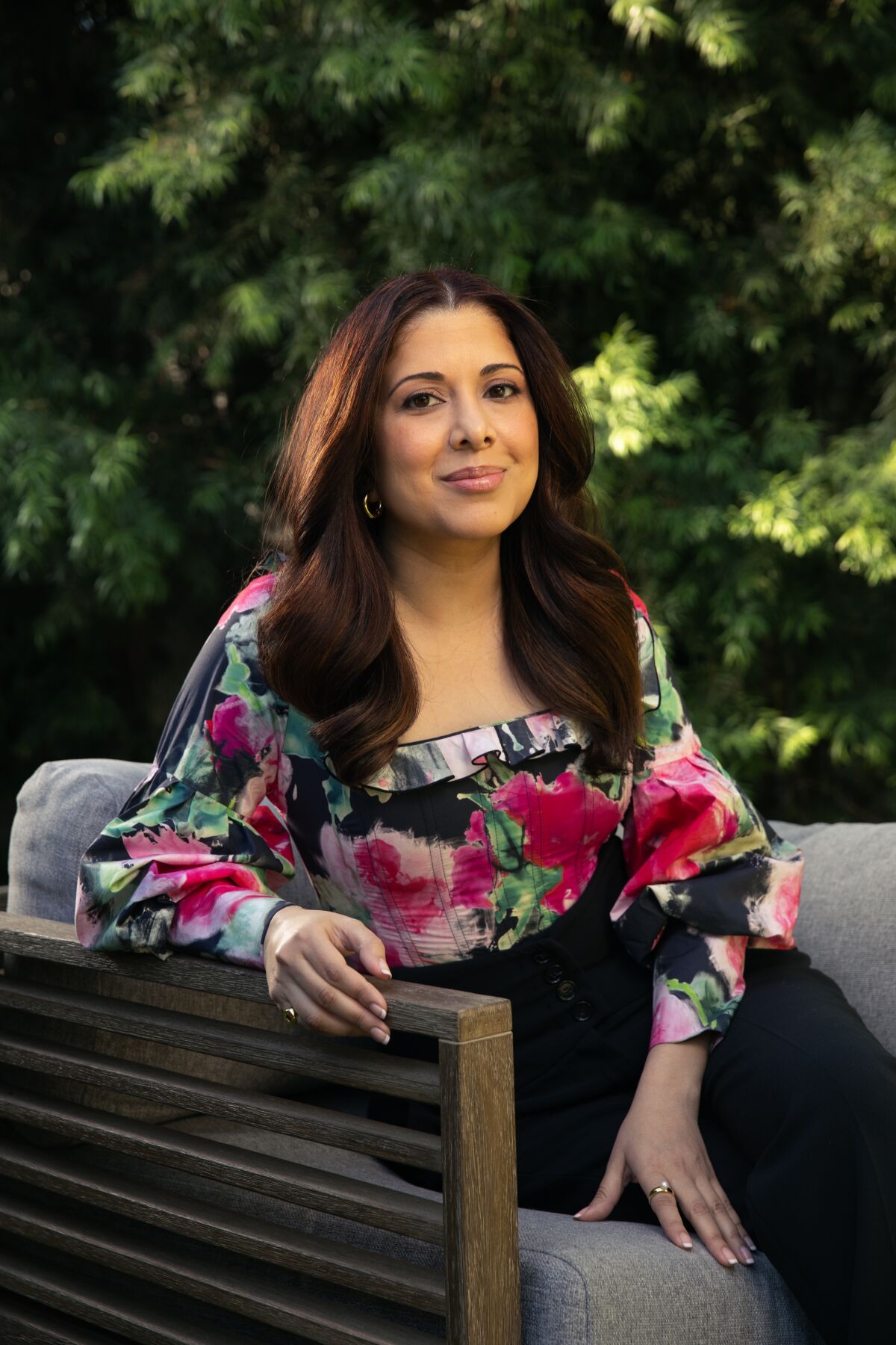 Vanessa Ramos, creator of the new Netflix sitcom "Blockbuster," sits on a chair outdoors her dwelling