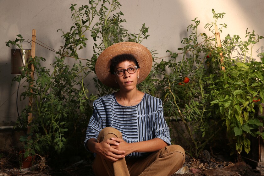 Gardener Jamie Renee Williams sits in front of vegetable plants.