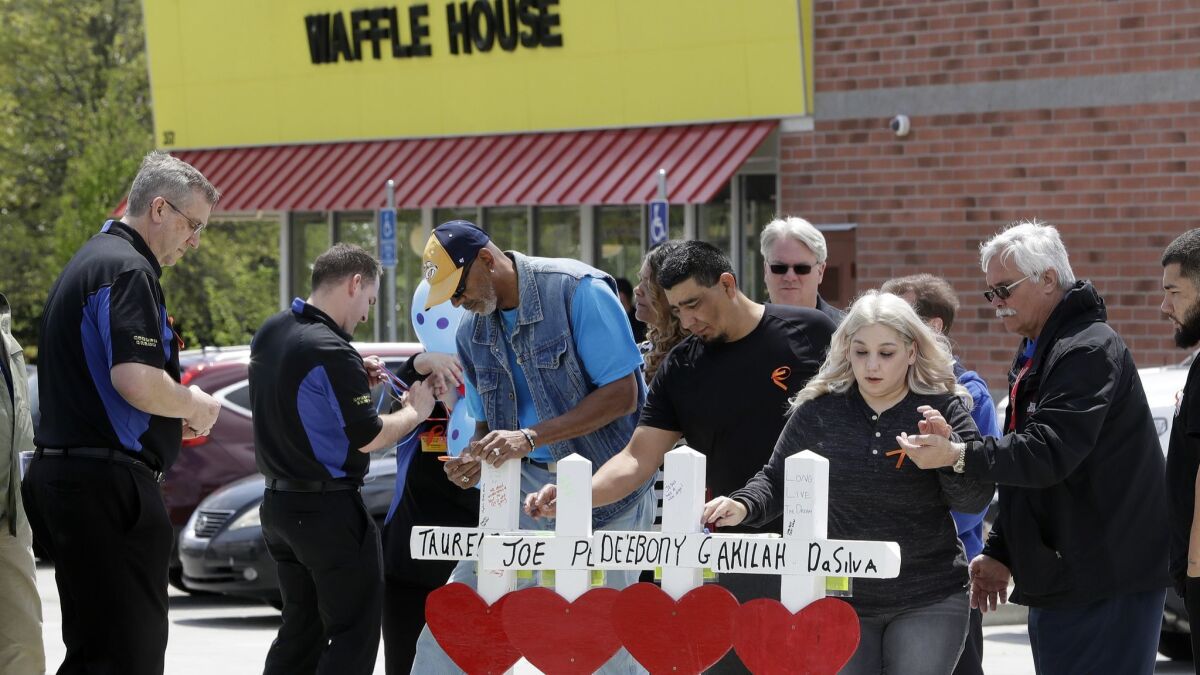 Family members of people killed at a Waffle House restaurant in Nashville write messages on wooden crosses set up as a memorial on April 25.