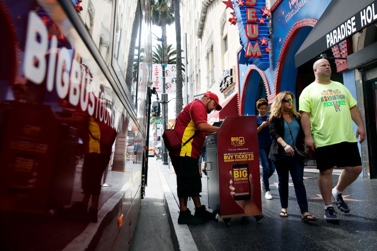 People pass a Big Bus boarding area on Hollywood Blvd. Big Bus is a subsidiary of a London-based tour bus franchise and has recently opened operations in Los Angeles.