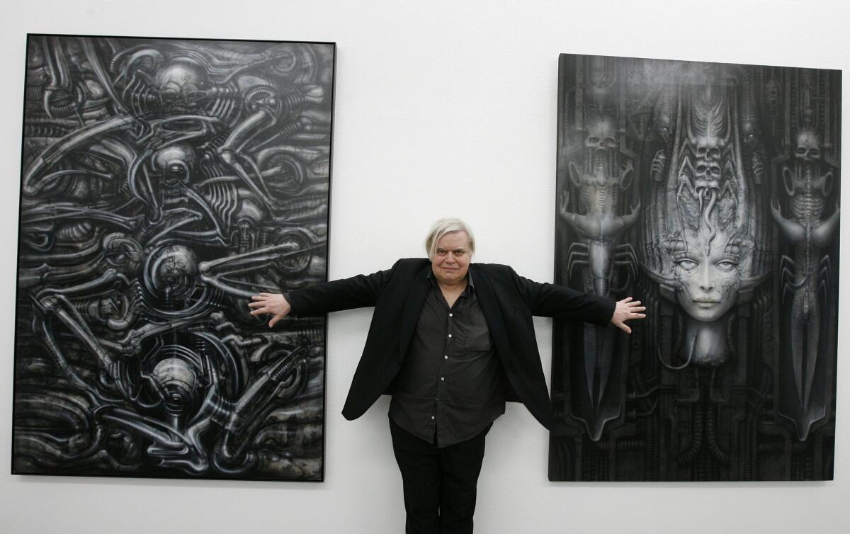 Swiss artist H.R. Giger poses with two of his works in 2007 in Switzerland.