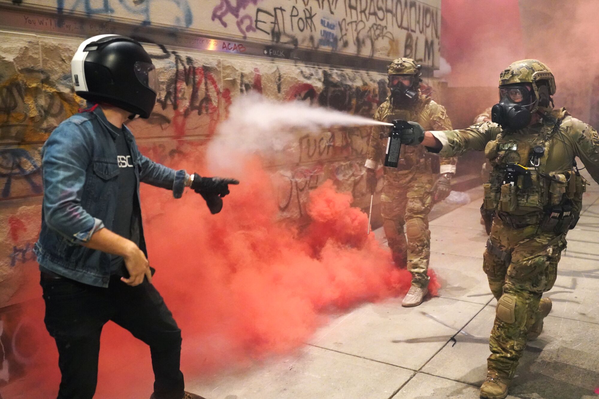 A federal officer pepper-sprays a protester in front of the federal courthouse in Portland, Ore., on Monday.