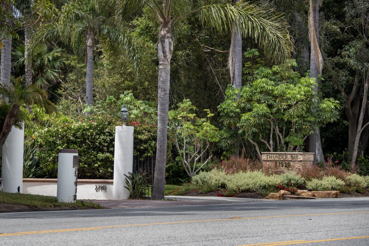 A pair of driveways are surrounded by trees and gates.