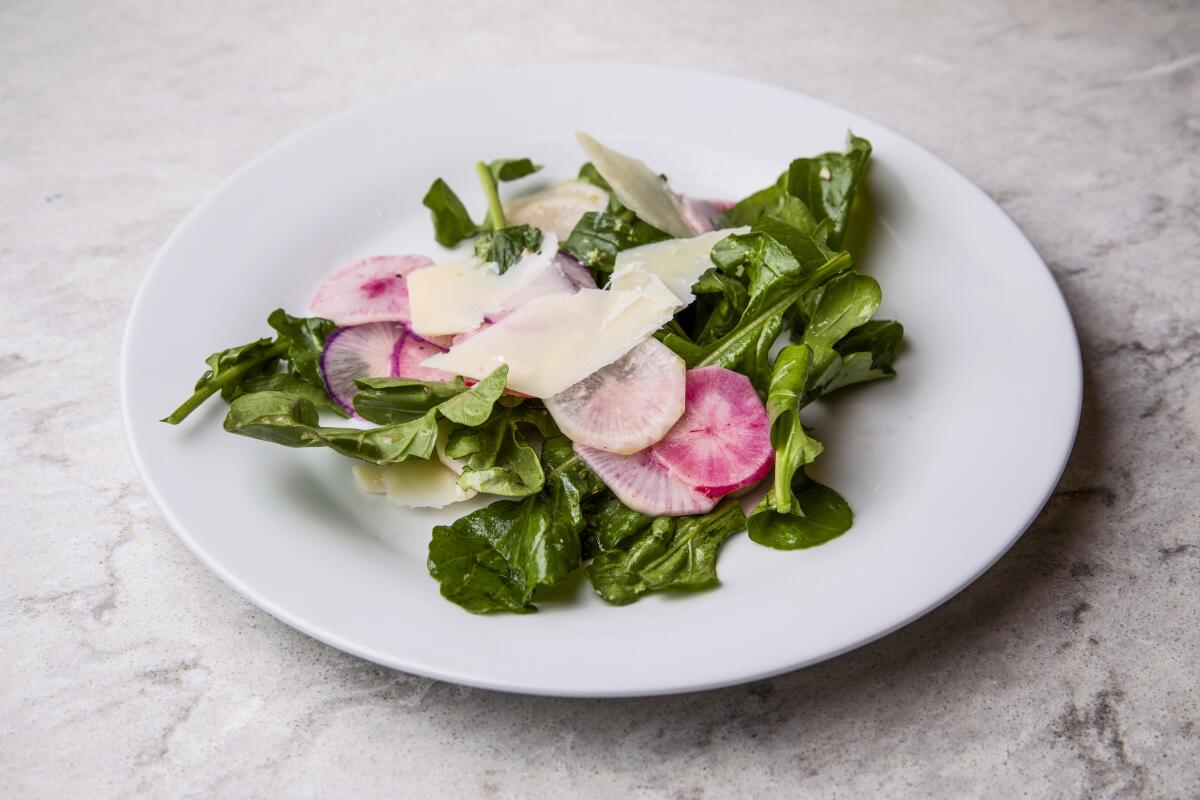 A plate of salad with sliced radish and cheese