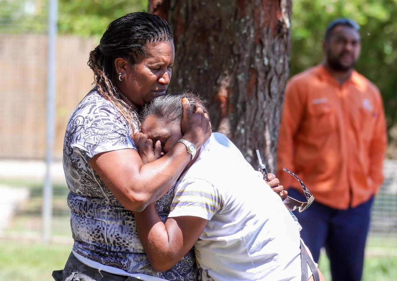 People believed to be relatives and friends of the victims grieve at the scene in Manoora, Australia.