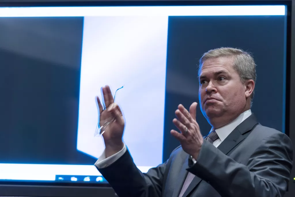 Laivastotiedustelun varajohtaja Scott Bray puhuu videonäytön edessä UAP-kuulemisen aikaan