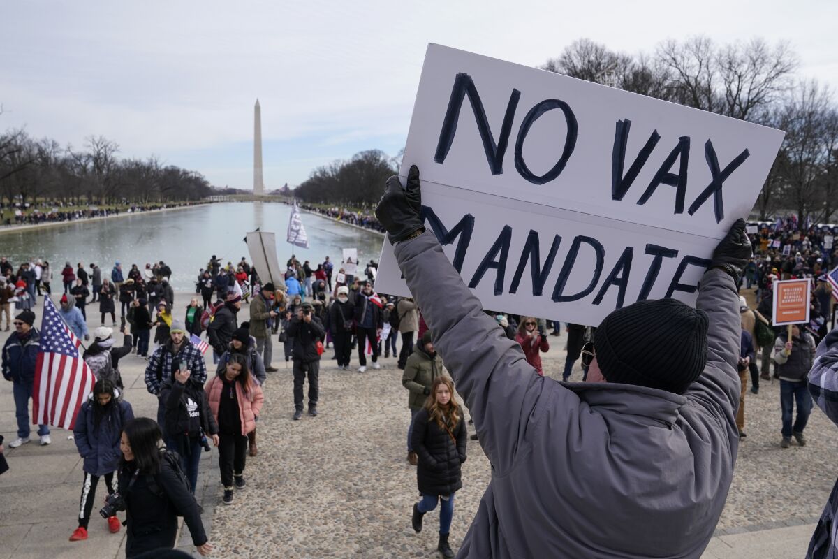 A person holds a sign that says "No vax mandate" at a protest at the Lincoln Memorial