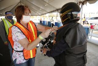 INGLEWOOD, CA - MARCH 01: Assistant principal of John Muir Middle School Rowel Salvador on his motorcycle receives his first COVID-19 Moderna vaccination shot from registered nurse Susan Domingo as LAUSD opened the nation's largest vaccination site specifically for education employees at SoFi stadium Monday morning using the Daily Pass, Los Angeles Unified's new technology and data system that coordinates health checks, COVID tests and vaccinations in one simple easy-to-use tool. The site is staffed by Los Angeles Unified school nurses and other licensed healthcare professionals and will have the capacity to administer thousands of vaccines daily for education staff. Anthem Blue Cross is providing volunteer clinical personnel and Cedars-Sinai has provided training to support this vaccination effort. SoFi Stadium on Monday, March 1, 2021 in Inglewood, CA. (Al Seib / Los Angeles Times).