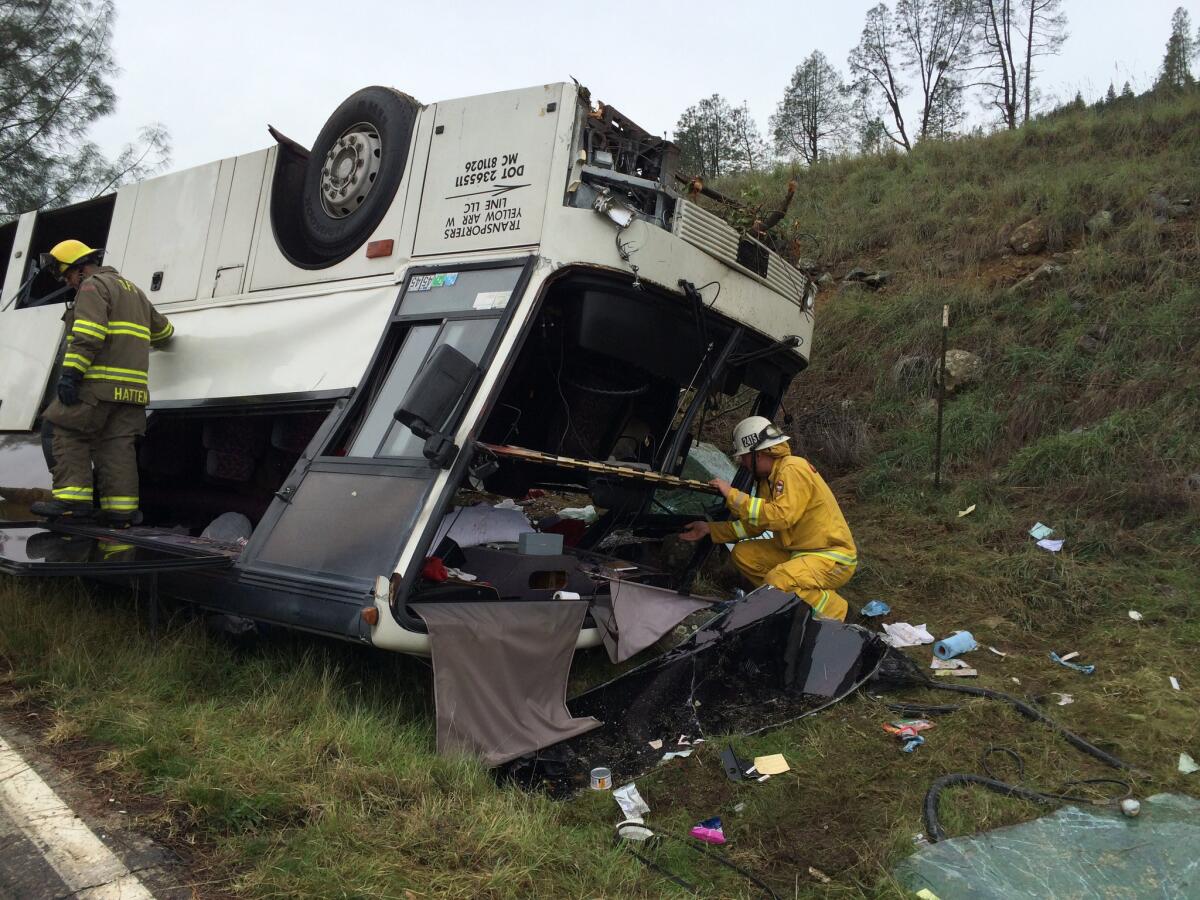 Emergency personnel check a tour bus that overturned just off Interstate 5, killing one person and sending dozens to hospitals near the Pollard Flat area in Redding, Calif., on Sunday.