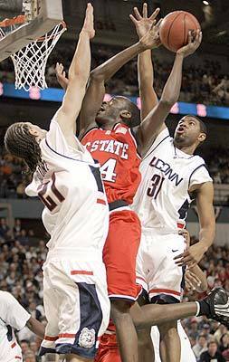 North Carolina State's Julius Hodge drives to the basket through Connecticut's Josh Boone, left, and Rashad Anderson, right.