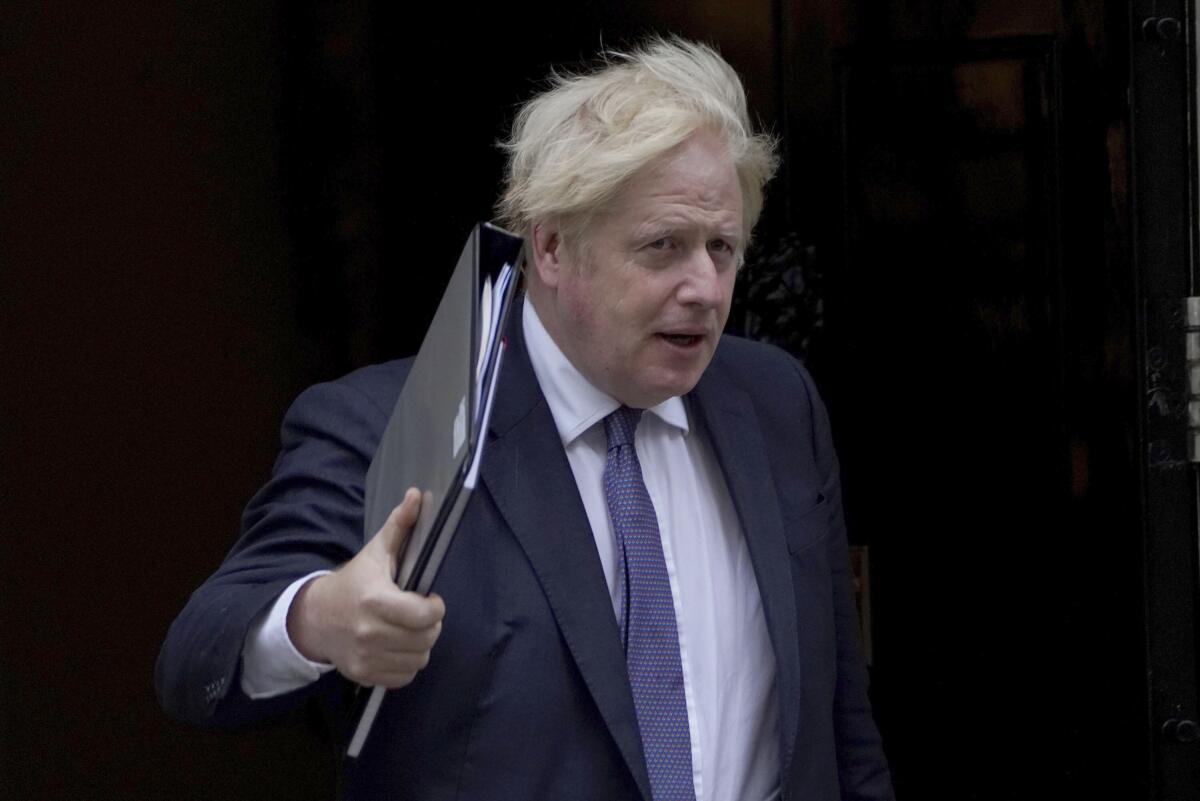 British Prime Minister Boris Johnson holds a binder of papers