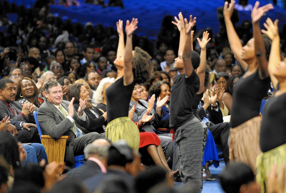 Cal State Chancellor Timothy White, third from left, applauds a group of dancers while attending a Sunday service at Crenshaw Christian Center in Los Angeles.