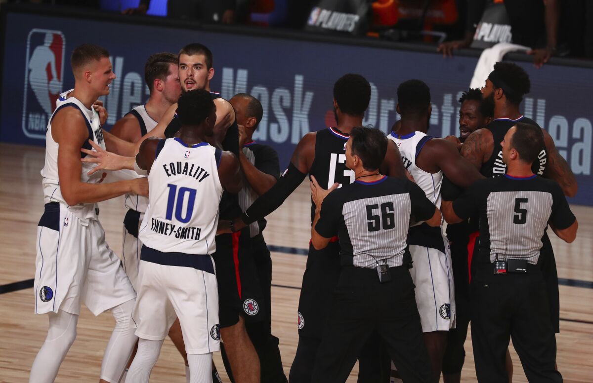 Officials separate the Dallas Mavericks and the Los Angeles Clippers after the teams got into a scuffle in Game 1 of an NBA basketball first-round playoff series, Monday, Aug. 17, 2020, in Lake Buena Vista, Fla. (Kim Klement/Pool Photo via AP)