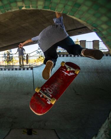 A skateboarder does a trick over a pedestrian tunnel.