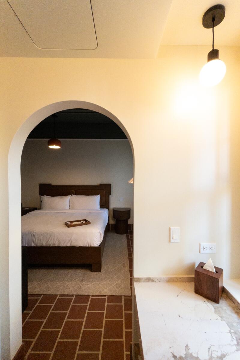 An arched doorway leads to a bedroom with a simply made double bed.