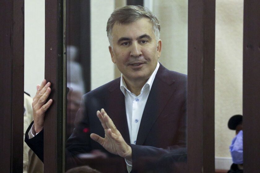 FILE - Former Georgian President Mikheil Saakashvili, who was convicted in absentia of abuse of power during his presidency and arrested upon his return from exile, gestures speaking from a defendant's dock during a court hearing in Tbilisi, Georgia, on Dec. 2, 2021. The main opposition party in Georgia has filed a court case calling for the imprisoned ex-president of the country to be released for medical examination overseas because of concerns that he is suffering from poisoning. (Irakli Gedenidze/Pool Photo via AP, File)