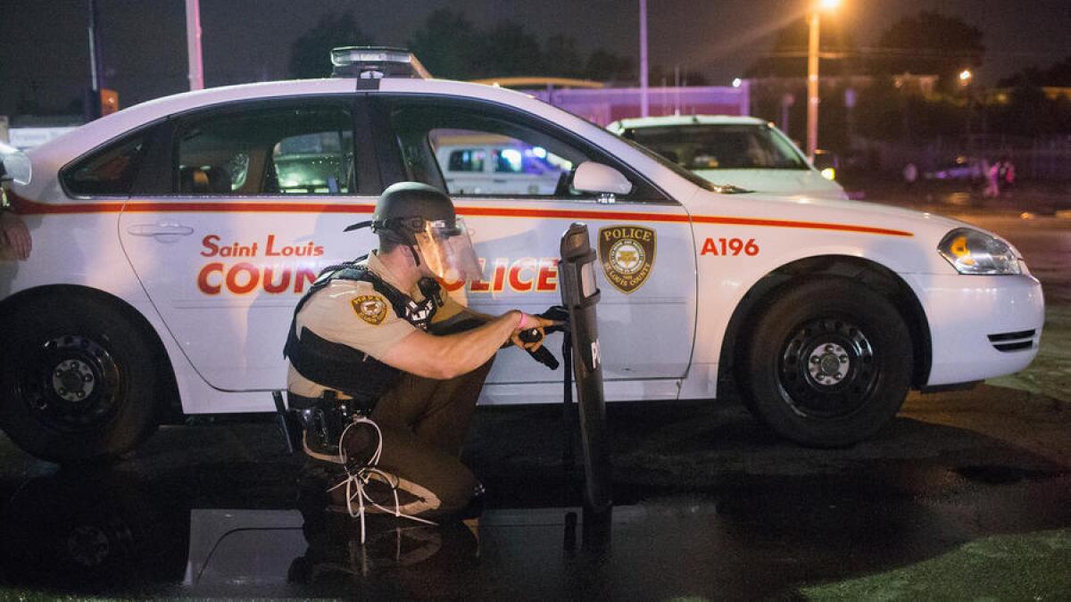 La policía se refugia mientras estallan los disparos durante una manifestación, realizada el 9 de agosto, en conmemoración al primer aniversario del asesinato a balazos de Michael Brown en Ferguson, Missouri.