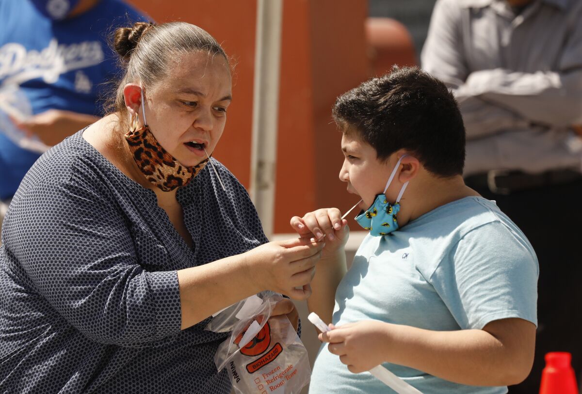  Edna Orante, 42, helps her son Damian Orante, 9, administer an oral swab test in Los Angeles