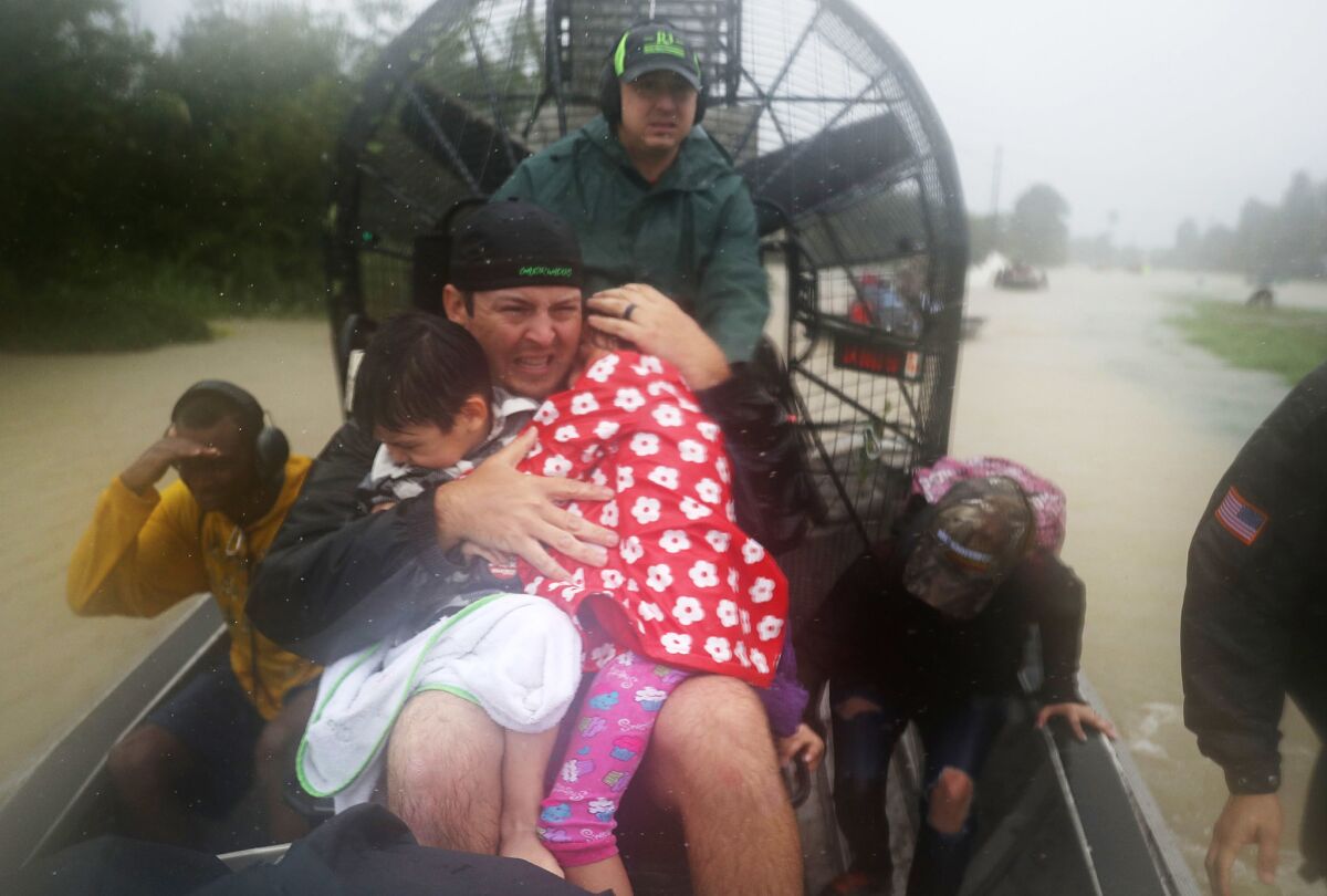 Dean Mize holds children as he and Jason Legnon use an airboat to rescue people from flooded homes in Houston