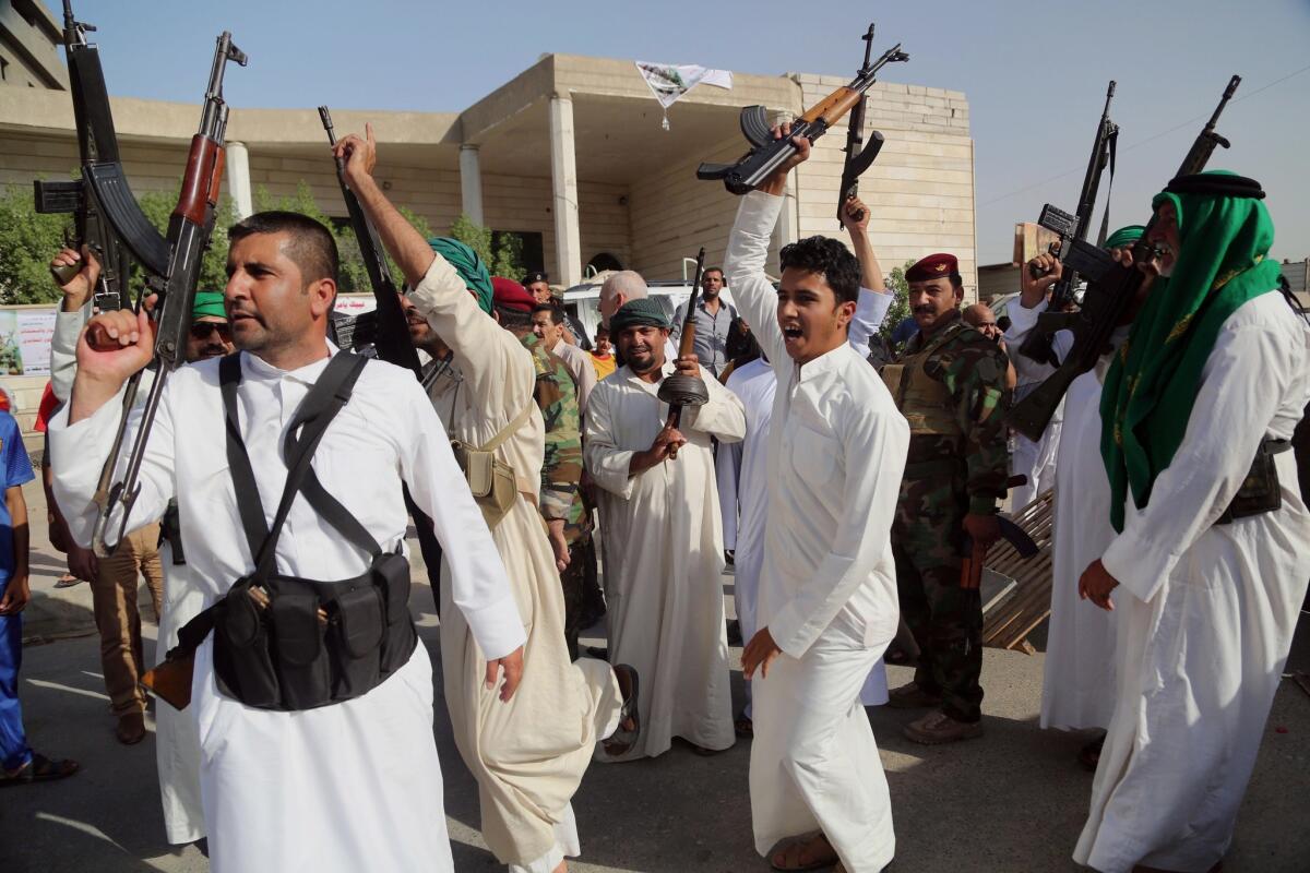 Iraqi Shiites in Basra raise their weapons and chant slogans against the Al Qaeda-inspired Islamic State of Iraq and Syria.