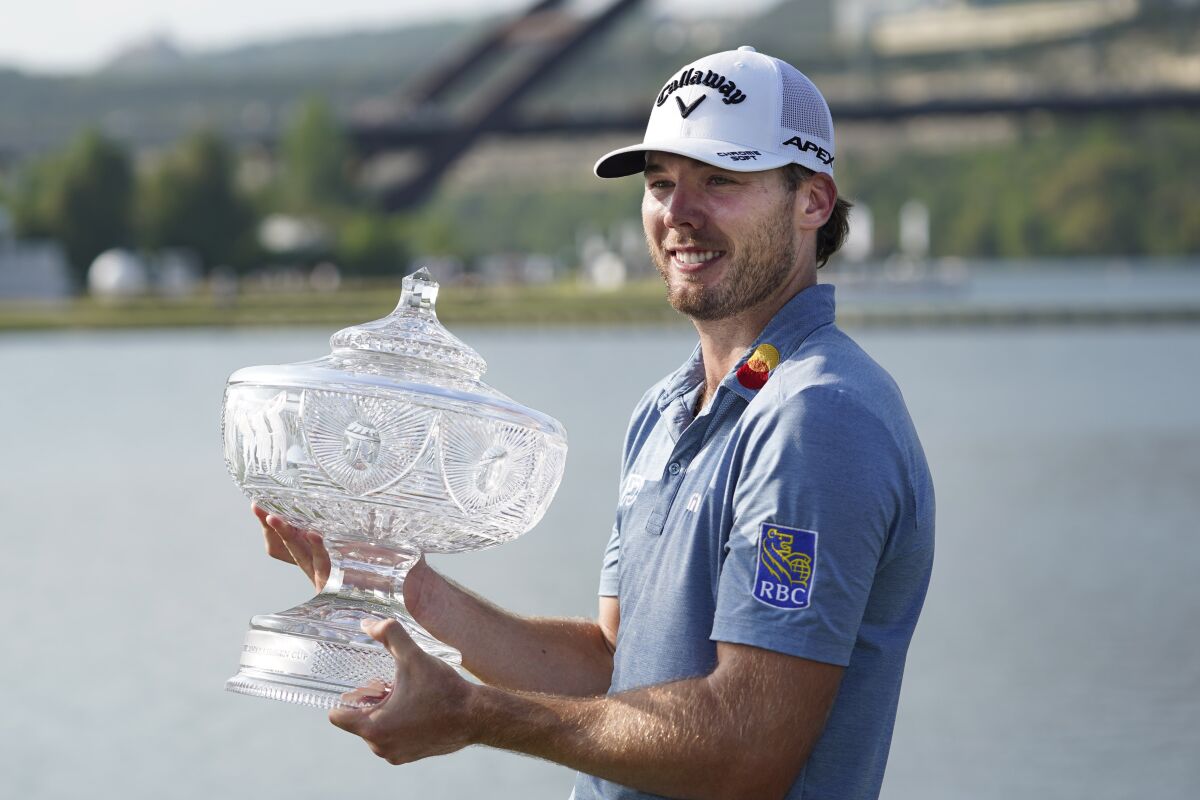 Sam Burns holds his trophy after defeating Cameron Young in the final match at the Dell Technologies Match Play Championship golf tournament in Austin, Texas, Sunday, March 26, 2023. Michael Dell, left, presented the trophy. (AP Photo/Eric Gay)