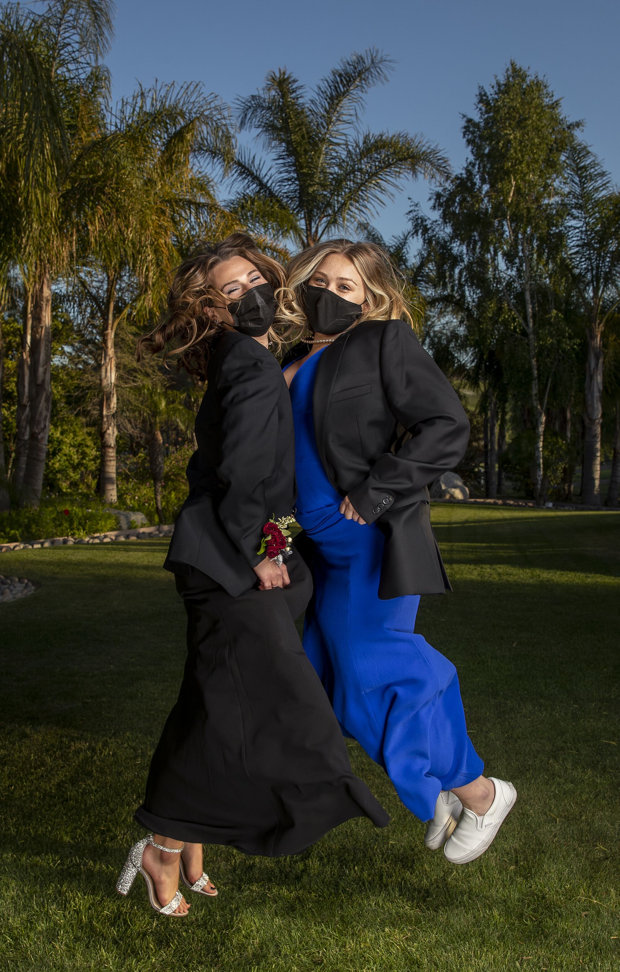 Two students strike a pose in formal wear and masks