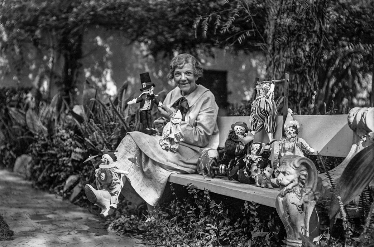 Harriet A. McCabe poses in a garden with dolls to be donated at Christmas. 