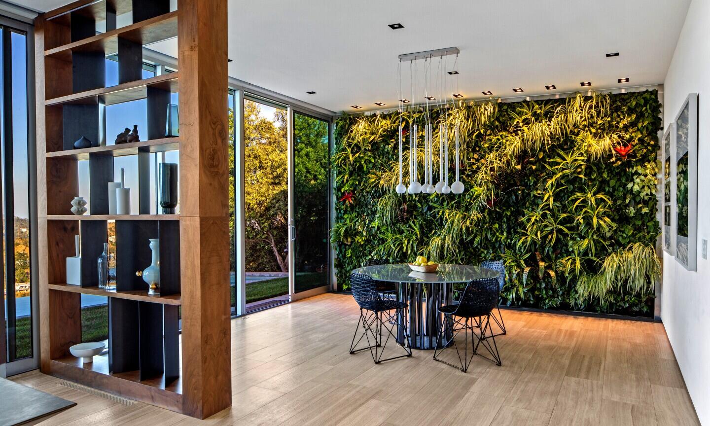 The dining room has a hanging light, furniture and a nearby shelf unit.