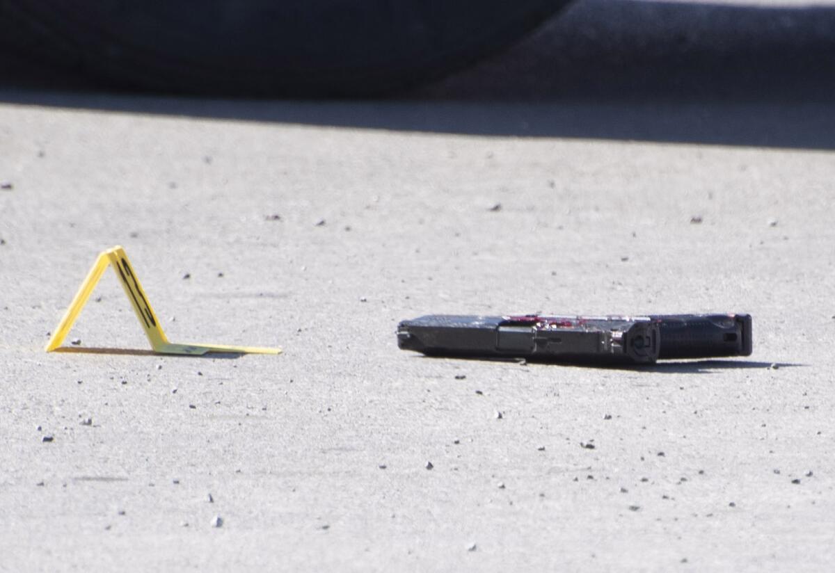 A handgun lays on the ground marked as evidence after a shooting in a Walmart parking lot in Duncan, Okl.