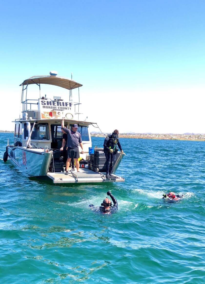A dive boat with divers in the water off the stern