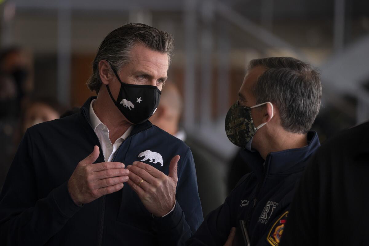 Gov. Gavin Newsom, left, talks to Los Angeles Mayor Eric Garcetti