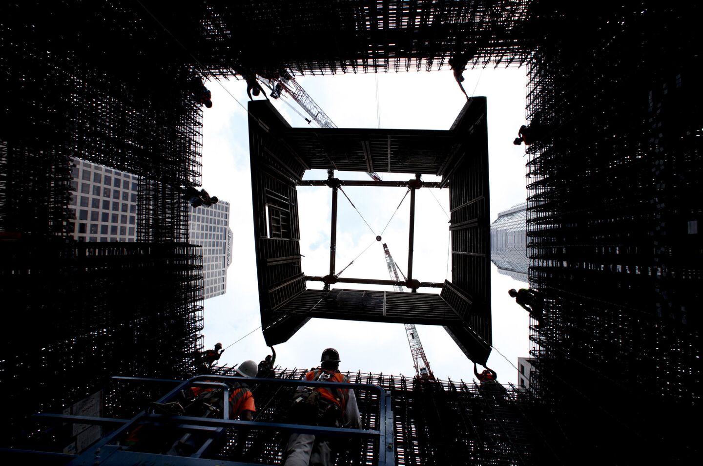 Construction workers guide a jumping wall form system into place as it is lowered into position by a crane into the core of the Wilshire Grand tower.