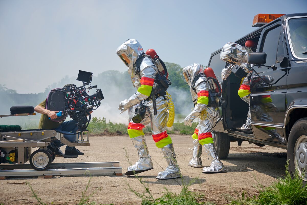 People in shiny, reflective hazmat suits are filmed on the set of 'White Noise'