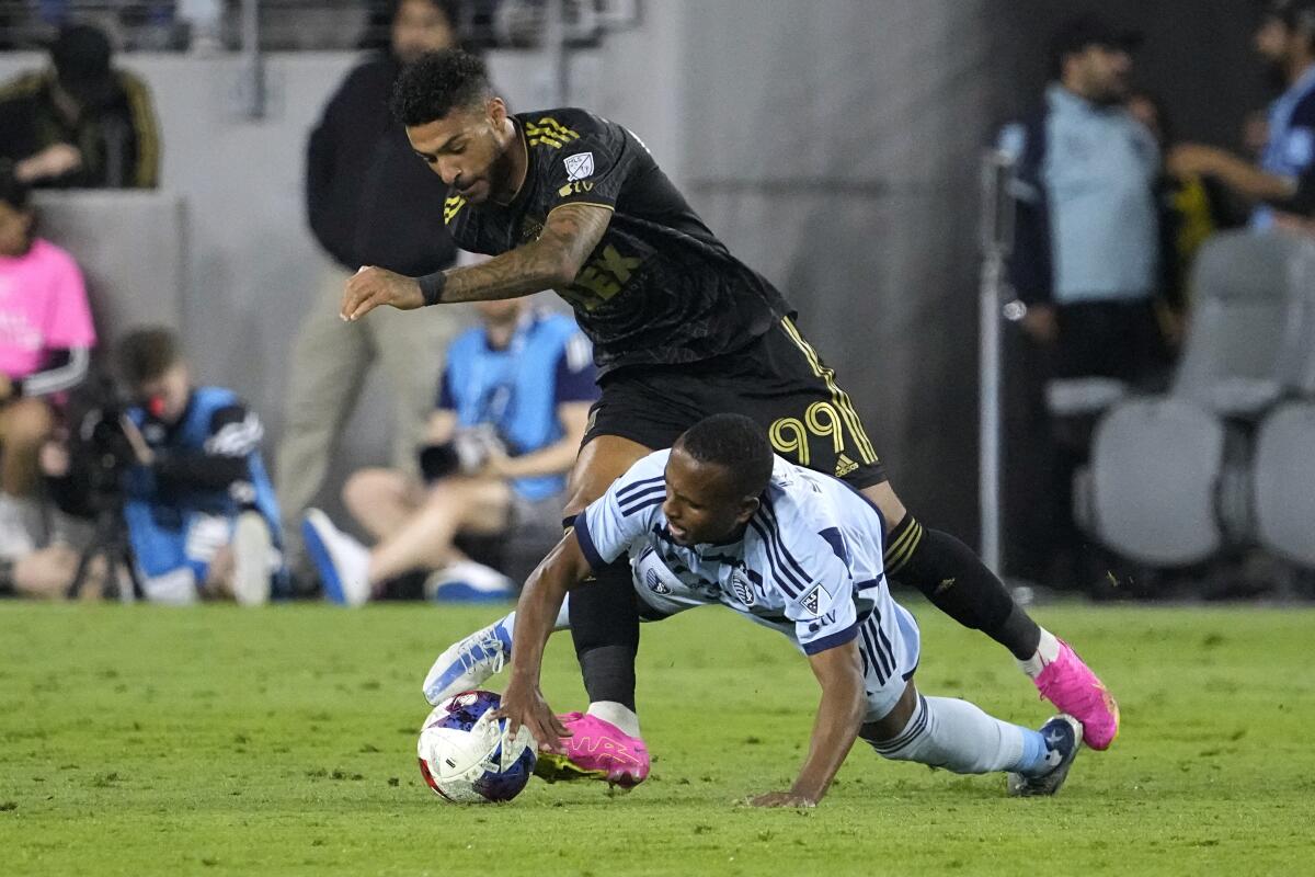 LAFC forward Denis Bouanga and Sporting Kansas City midfielder Gadi Kinda tangle on the field.