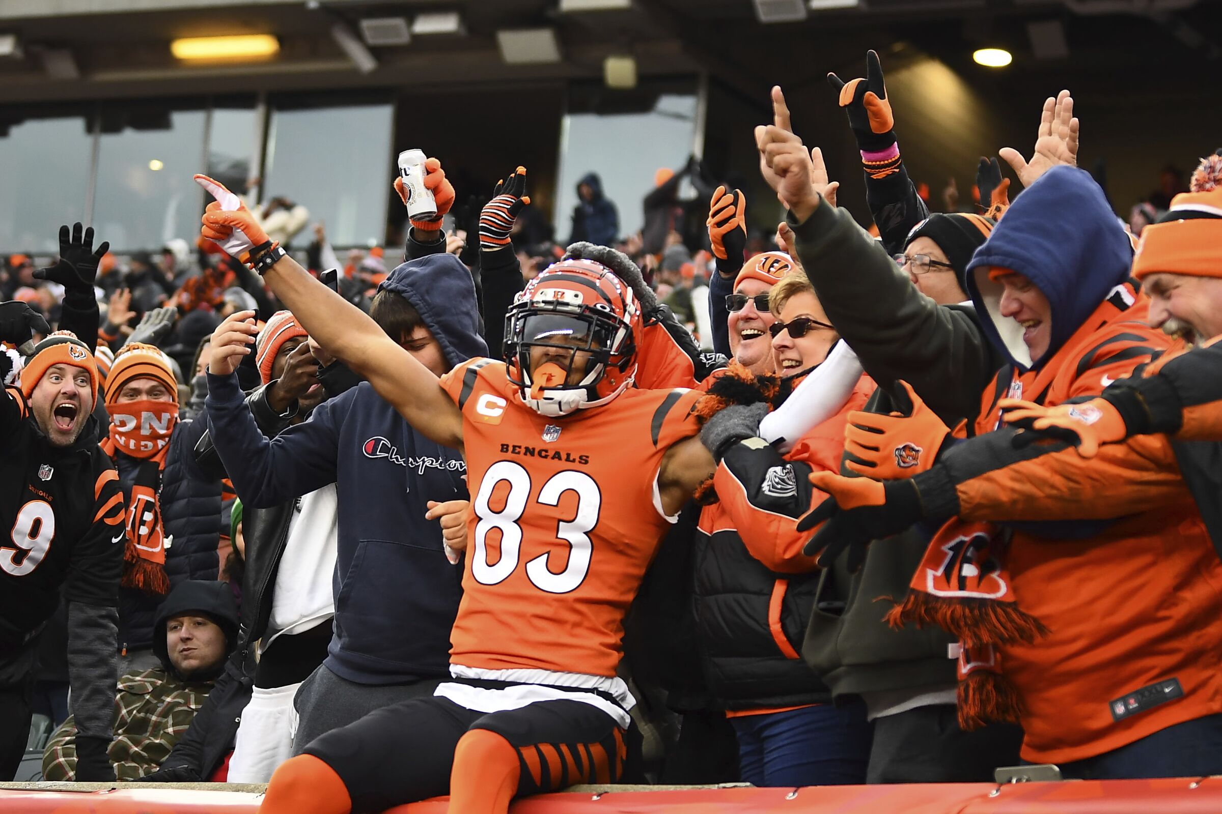 Cincinnati Bengals wide receiver Tyler Boyd sits on a ledge and celebrates a touchdown with fans 