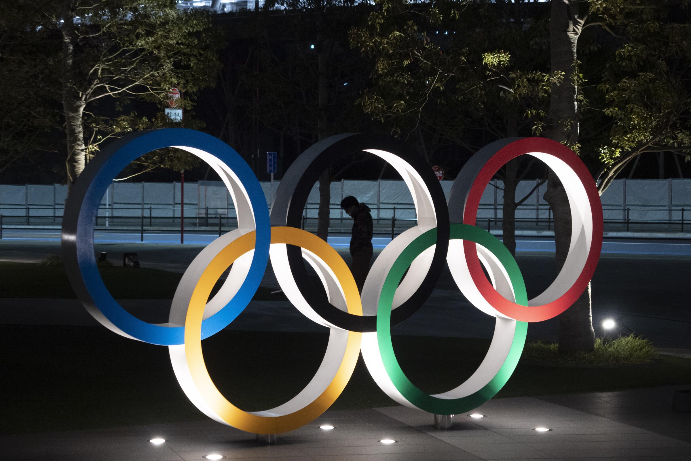A man is seen through a display of the Olympic rings in Tokyo.