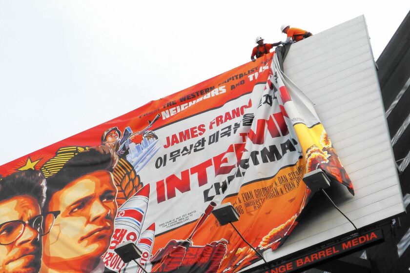 Workers remove a poster for "The Interview" from a billboard in Hollywood on Thursday after Sony decided to cancel the movie's Christmas release.